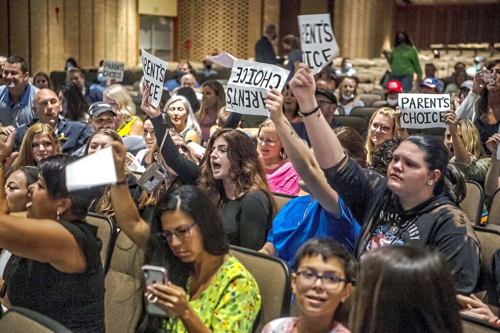 People hold signs and chant during a meeting of the North Allegheny School District school board regarding the district's mask policy