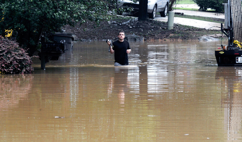 Man wades through flooded neighborhood 