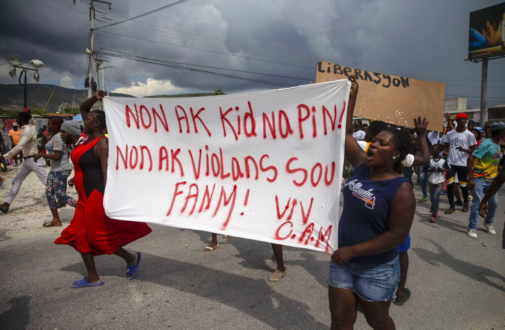 People protest carrying a banner with a message that reads in Creole: "No to kidnappings, no to violence against women ! Long live Christian Aid Ministries," demanding the release of kidnapped missionaries, in Titanyen, north of Port-au-Prince, Haiti