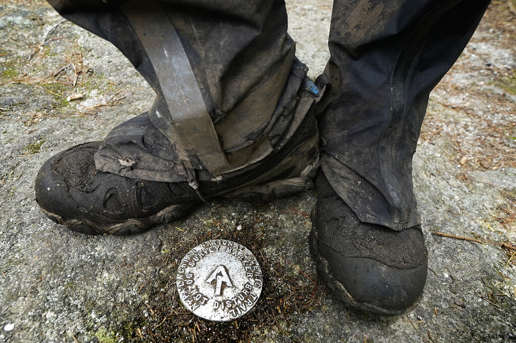 M.J. Eberhart, 83, pauses by a survey marker on the Appalachian Trail, Sunday, Sept. 12, 2021, in Gorham, New Hampshire. Eberhart, who goes by the trail name of Nimblewill Nomad, has hiked all of the country