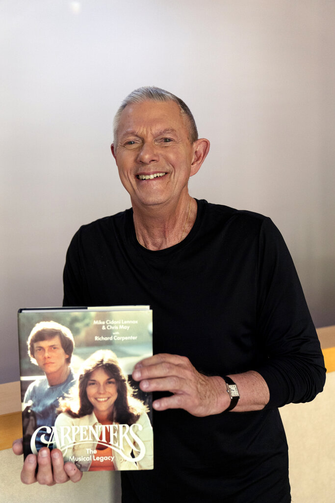 Richard Carpenter smiles as he poses with his new book: "Carpenters: The Musical Legacy," at his home in Thousand Oaks, Calif.