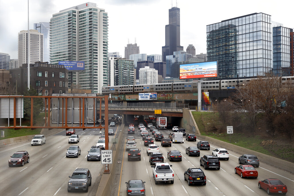 Traffic flows along Interstate 90 highway as a Metra suburban commuter train moves along an elevated track in Chicago