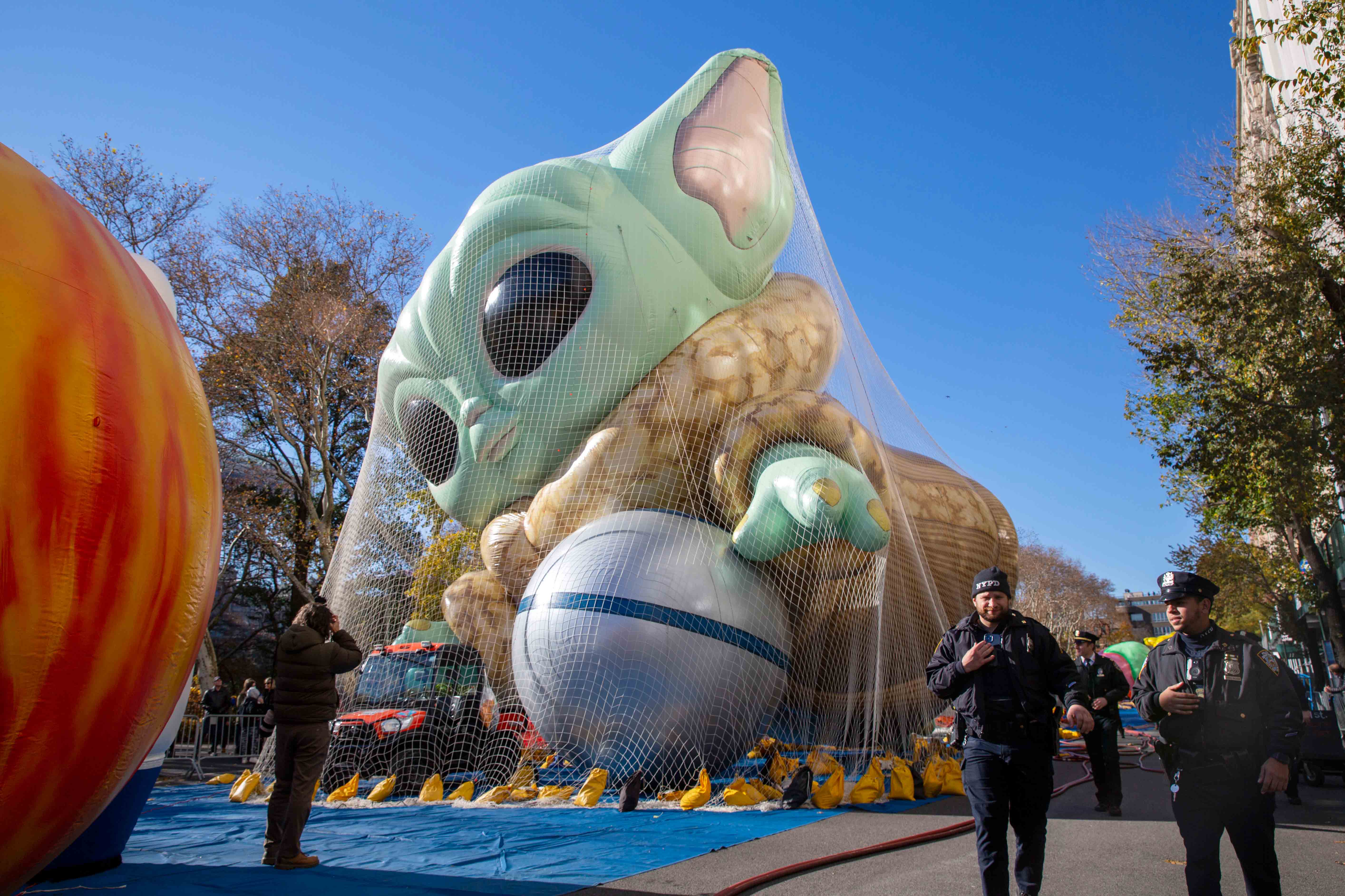 Police walk by an inflated helium balloon of Grogu, also known as Baby Yoda, from the Star Wars show The Mandalorian, Wednesday, Nov. 24, 2021, in New York, as the balloon is readied for the Macy