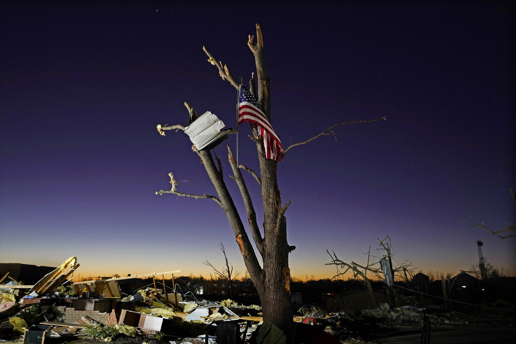 Flag hangs from damaged tree after tornado in Mayfield, Ky.  