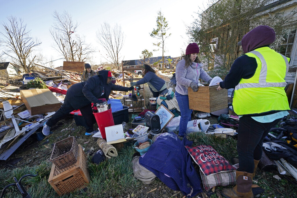 Volunteers, mostly from the Mayfield Consumer Products factory, help salvage possessions from the destroyed home of Martha Thomas, in the aftermath of tornadoes that tore through the region several days earlier, in Mayfield, Ky., Monday, Dec. 13, 2021