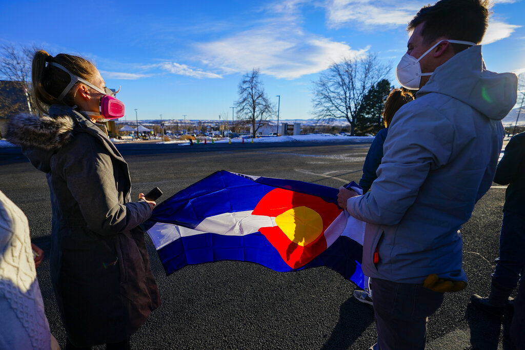 Kelsey Taylor and brother Jeff Alexander hold a Colorado flag while waiting for President Joe Biden