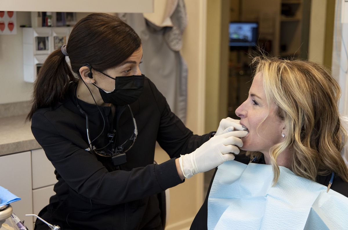 Dr. Rana Stino, left, checks the retainer fit on patient Holly Brown 