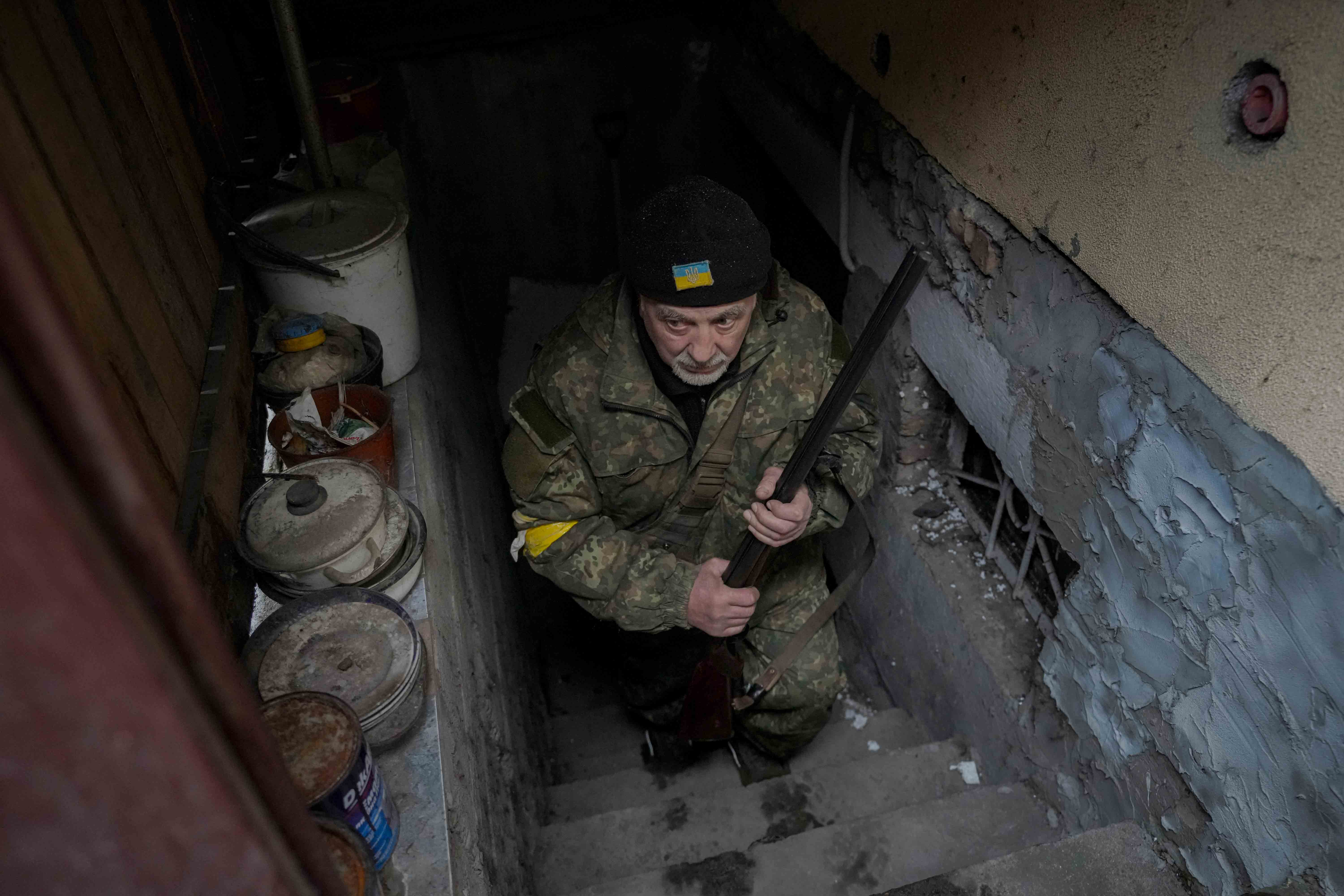 Andrey Goncharuk, 68, a member of territorial defense, clutches a hunting rifle while coming out of a small basement of a house crowded with people seeking shelter from Russian airstrikes and shelling in Gorenka, outside the capital Kyiv, Ukraine, Wednesday, March 2, 2022.