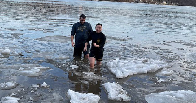 Man following female cadet out of icy river waters