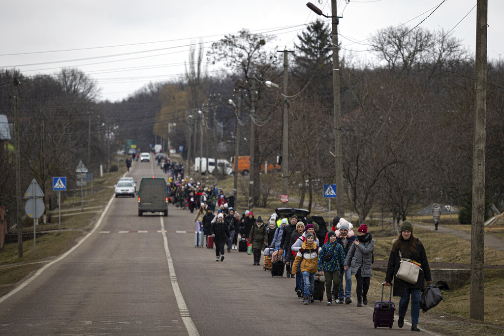 Groups of Ukrainian refugees walk along a road near Volytsya, Ukraine 