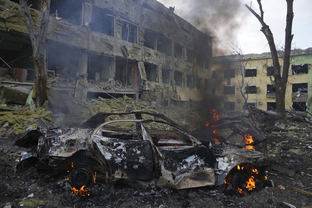 A car burns at the side of the damaged by shelling maternity hospital in Mariupol, Ukraine