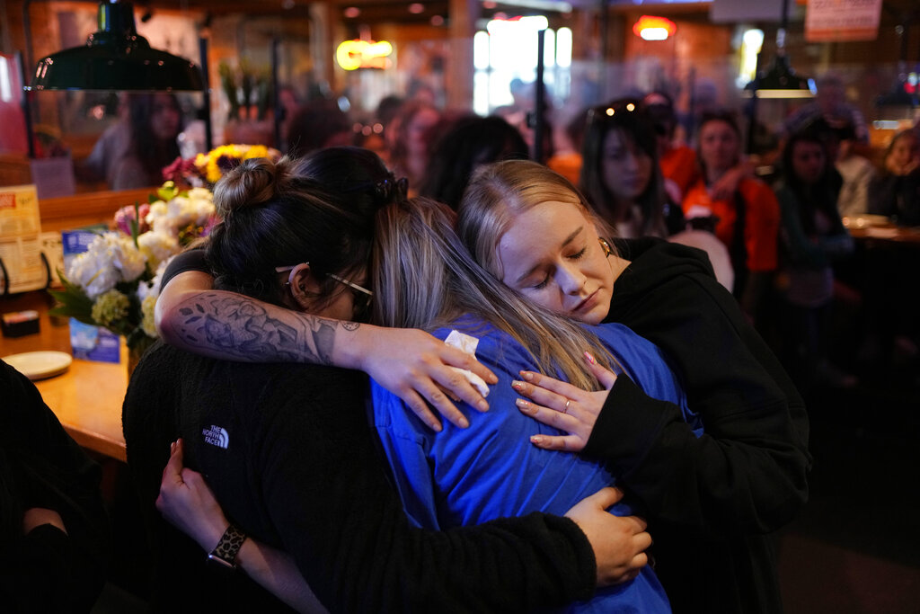 Emily Funderburk, right, embraces friends and coworkers during a memorial for Jackson Zinn at a Texas Roadhouse restaurant