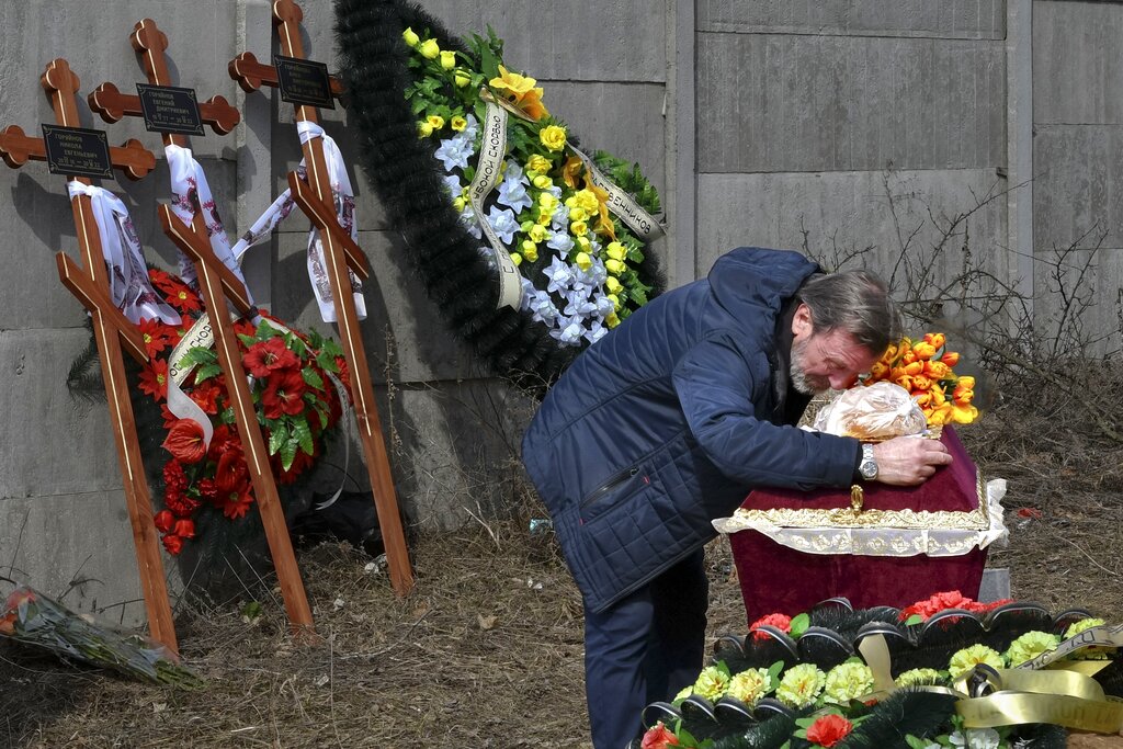 A relative mourns on the coffin with the body of 3 year-old Mykola Goryainiv, who died with his parents as they were driving a car trying to evacuate from a fighting zone in Kharkiv region