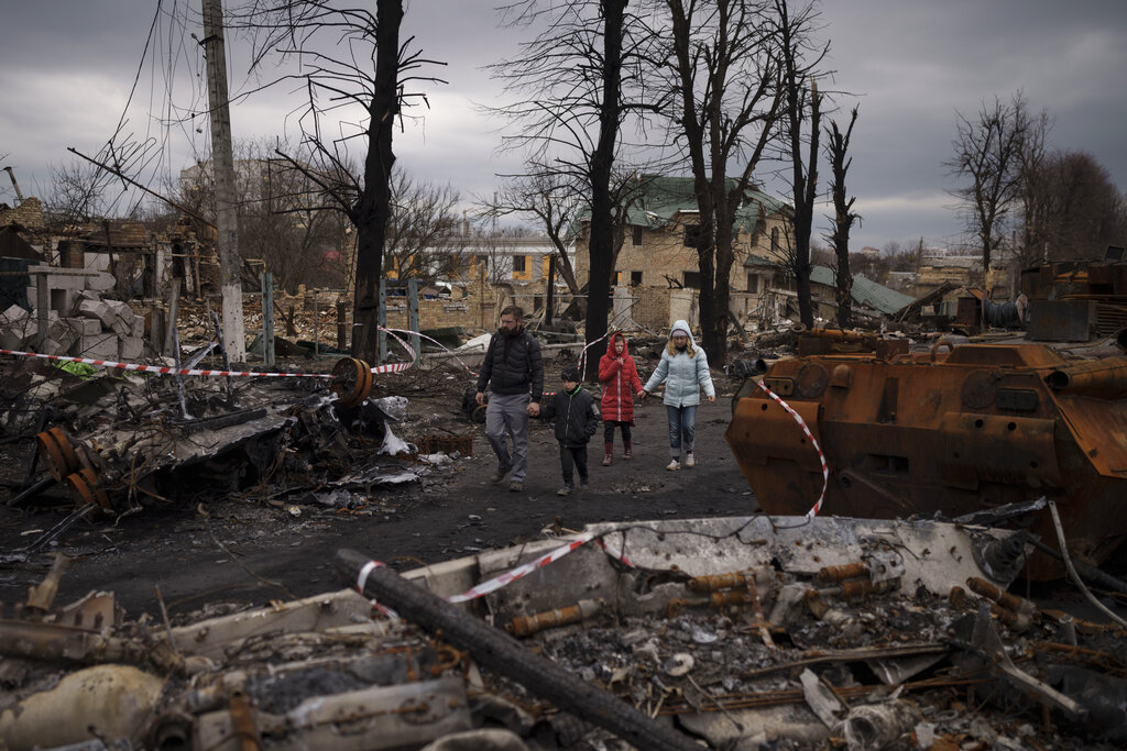 A family walks amid destroyed Russian tanks in Bucha, on the outskirts of Kyiv, Ukraine 