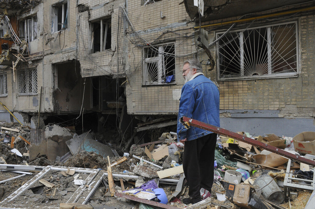 A man stands next to an apartment building damaged by shelling in Kharkiv, Ukraine