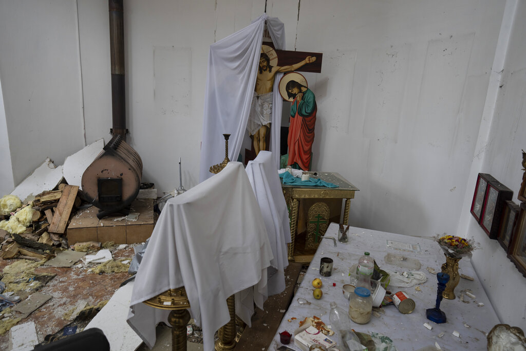 A wooden crucifix is half covered with a white sheet inside a damaged church following a Russian attack in the previous weeks in the town of Makarov , Kyiv region