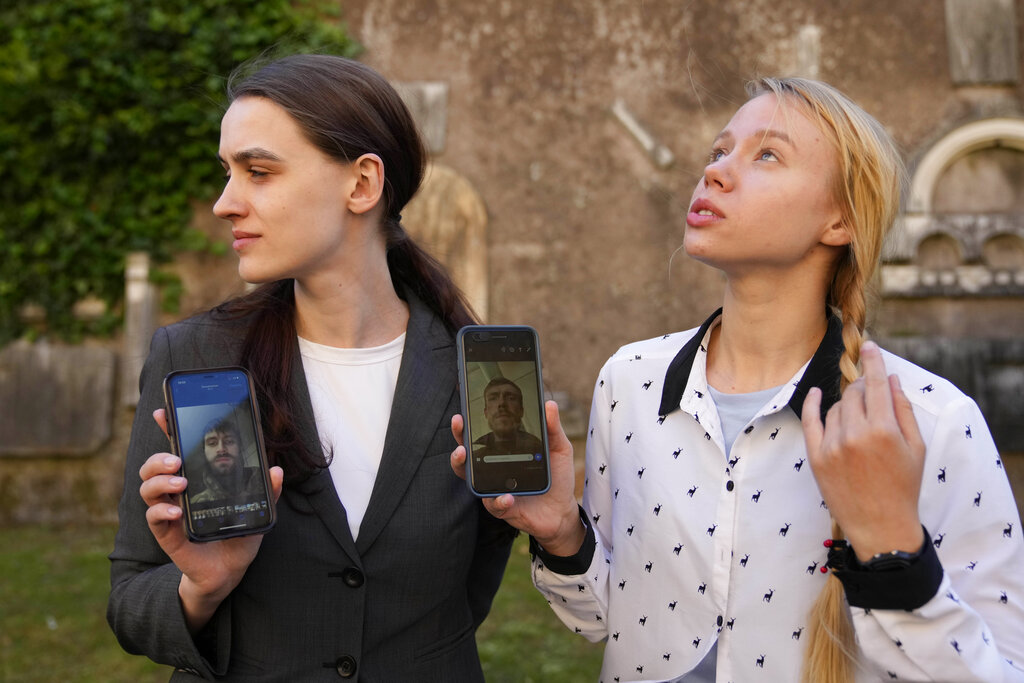 Kateryna Prokopenko, wife of Denys Prokopenko, commander of the Azov regiment, right, and Yulia Fedosiuk, wife of Arseny Fedosiuk, another member of Azov regiment get emotional as they show photos of their husbands on their phones during an interview