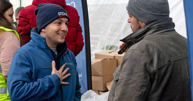 Convoy staff man wearing beanie talks to refugee