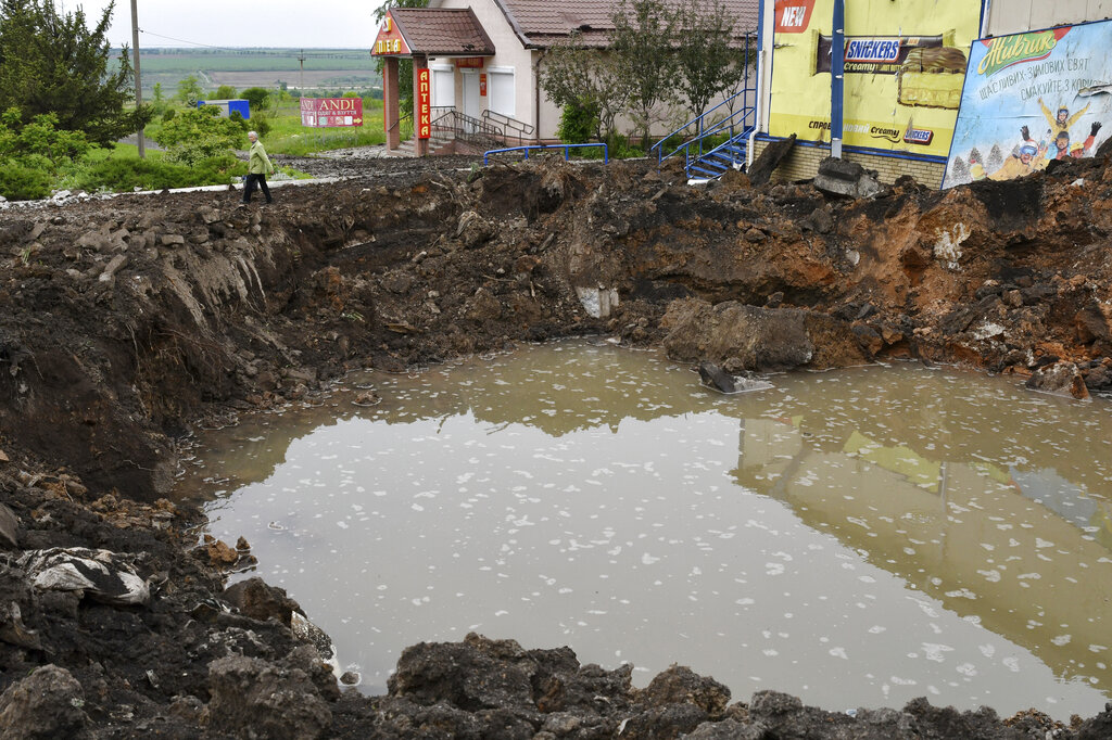 A woman walks past a crater of an explosion after Russian shelling in Soledar, Donetsk region, Ukraine