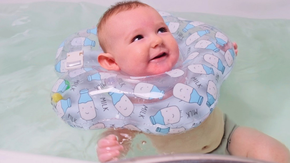 Baby floating in water with an inflatable item around its neck