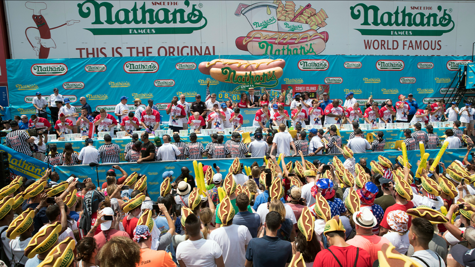 Crowd watches contestants eat the most hotdogs.