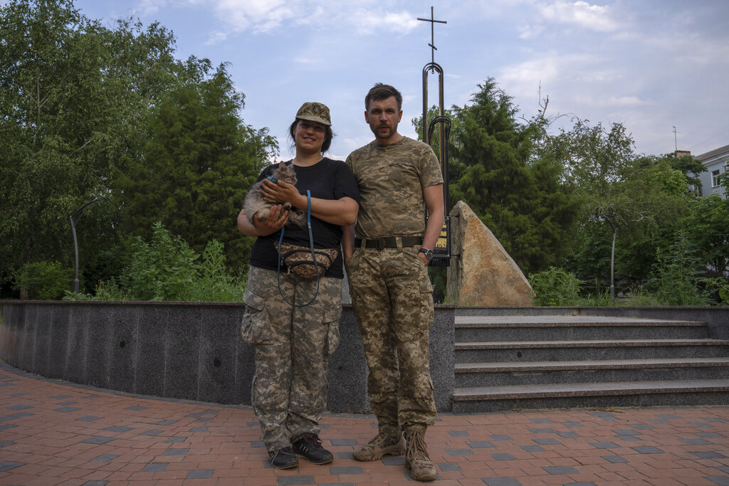 Ukrainian soldier Valentyna with her cat and boyfriend partner Vitalii, right, take a walk in the main square of Kramatorsk, Ukraine