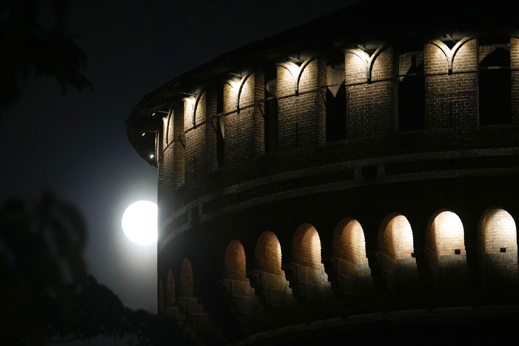 The full moon rises over the Sforzesco Castle, in Milan, Italy, Wednesday, July 13, 2022.