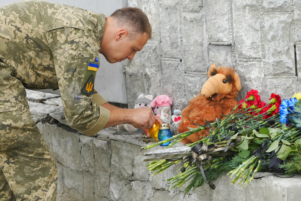 Ukrainian serviceman lights a candle at the site of a Russian shelling on Thursday, in Vinnytsia, Ukraine