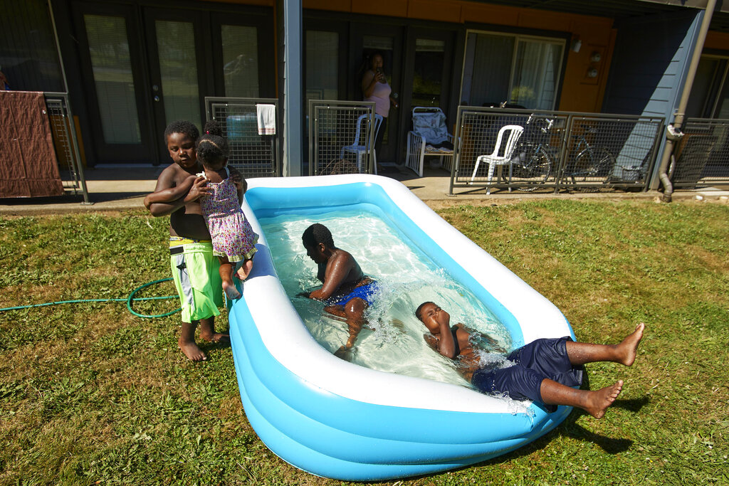 Jalen Askari, 7, right, plugs his nose as he falls into the pool he is playing in with his siblings, from left, Amari, 5, Bella, 2, and DJ, 10, in Portland, Ore.
