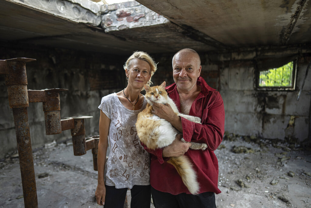 Zhanna Dynaeva and Serhiy Dynaev stand with a cat inside their house which was destroyed by Russian bombardment, in the village of Novoselivka, near Chernihiv, Ukraine