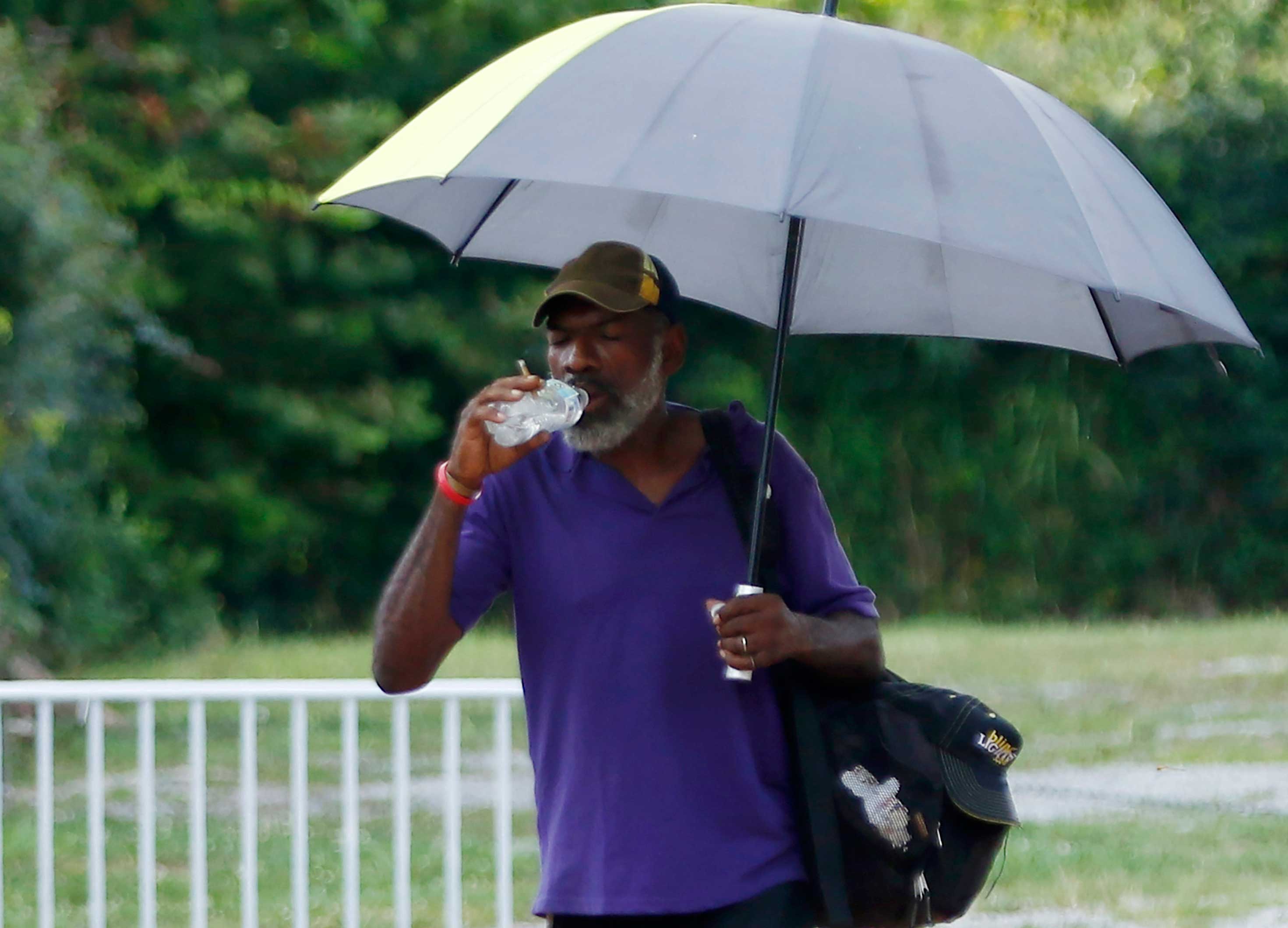 Man with umbrella and water bottle in heat