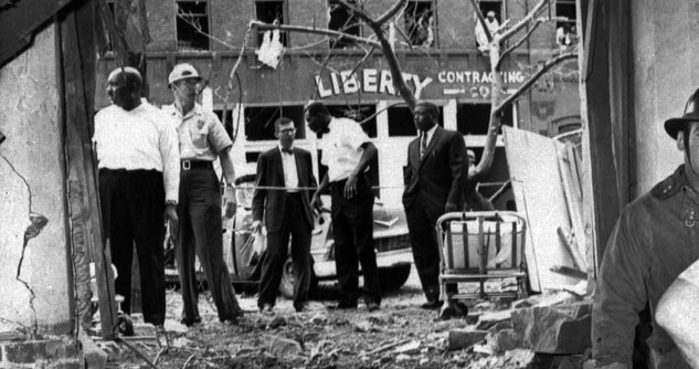 People standing around a bombed-out building