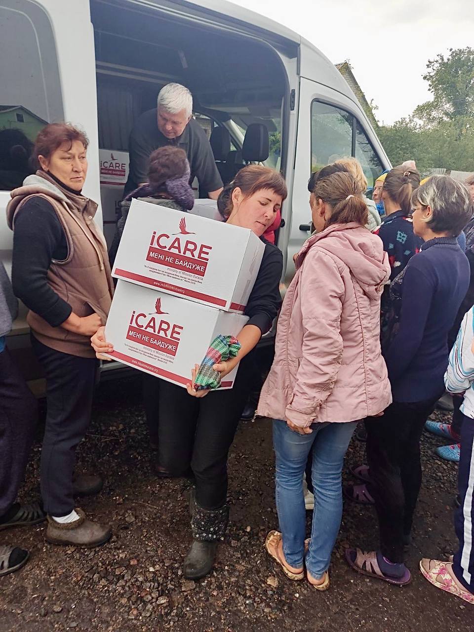 A woman carries two iCare food boxes from a distribution van in Balakliya 