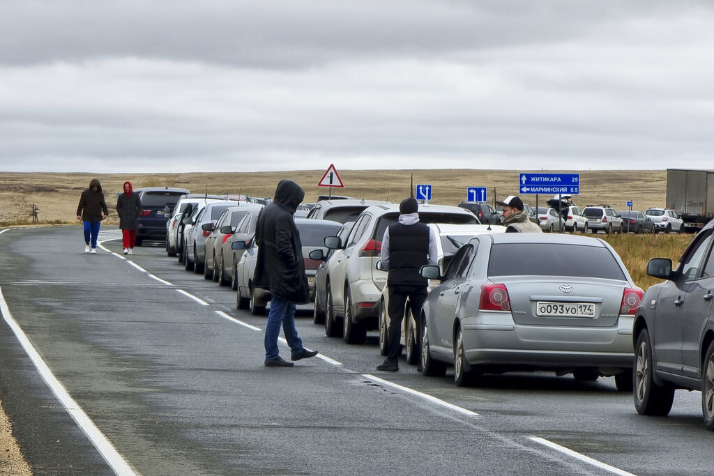 People walk next to their cars queuing to cross the border into Kazakhstan