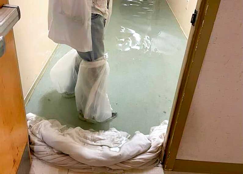 a staff member stands in a flooded hallway at HCA Florida Fawcett Hospital in Port Charlotte, Fla.