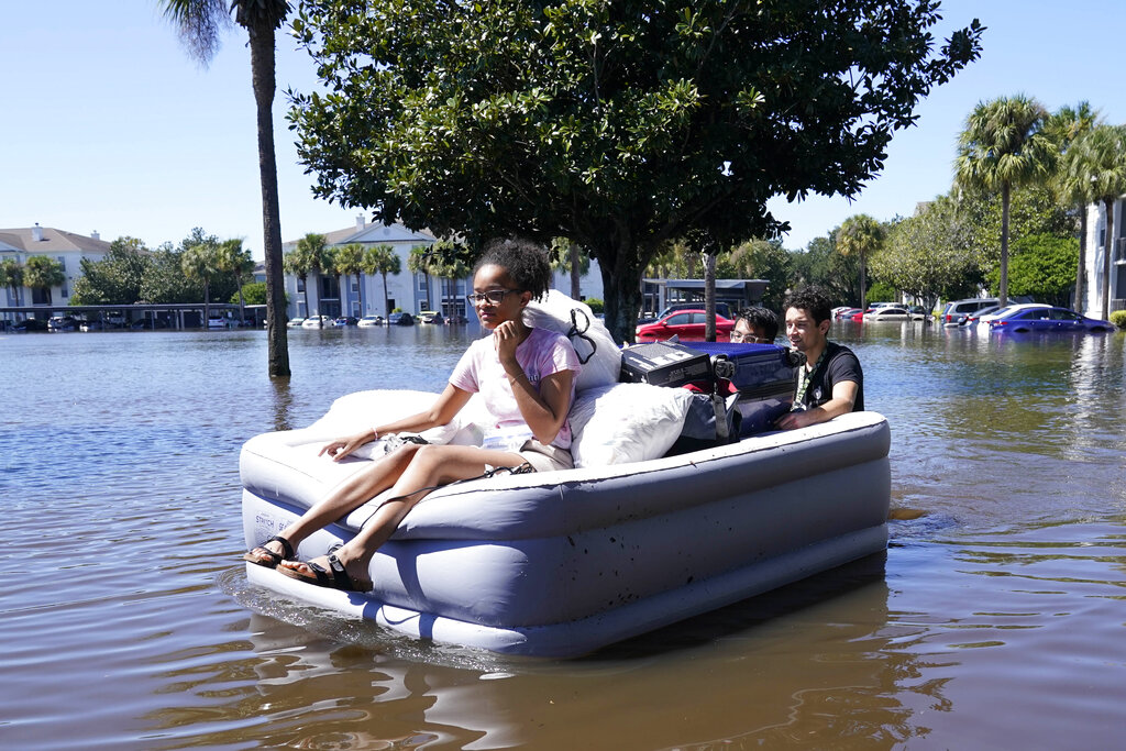 University of Central Florida students use an inflatable mattress as they evacuate an apartment complex near the campus that was totally flooded by rain from Hurricane Ian in Orlando