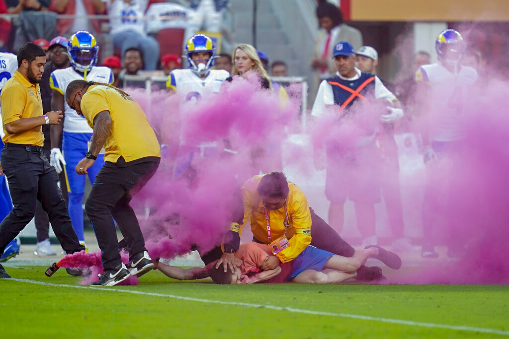 A protester is held down by security after running on the field during the first half of an NFL football game between the San Francisco 49ers and the Los Angeles Rams