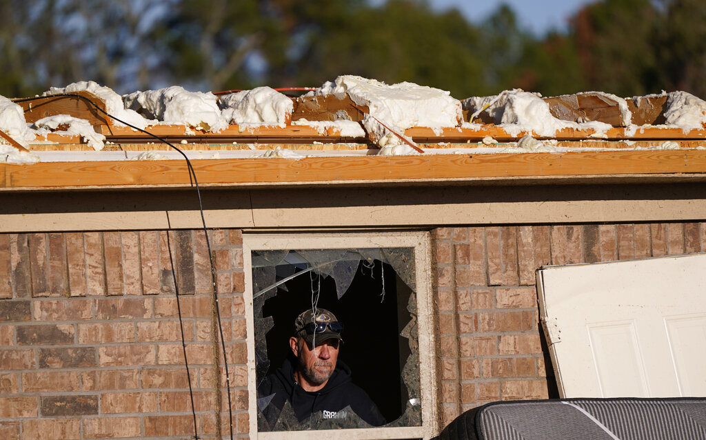 A man looks out of a broken window from a home that was destroyed by a tornado in Powderly, Texas