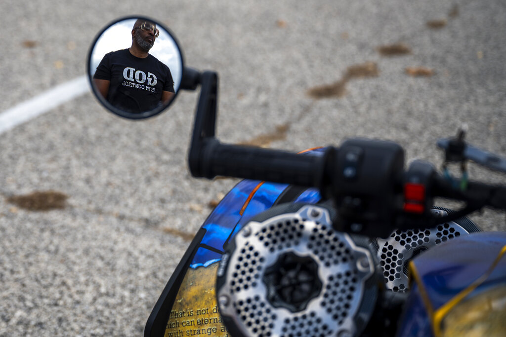 Yusuf Jackson is seen reflected in a motorcycle mirror wearing a shirt reading "God is in Control" during a "Black Bikers Vote