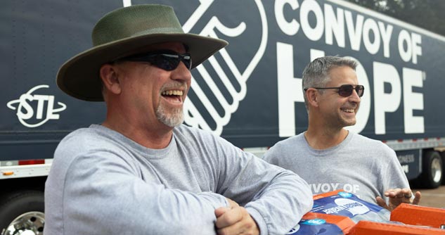 Convoy of Hope workers smile in front of a big rig