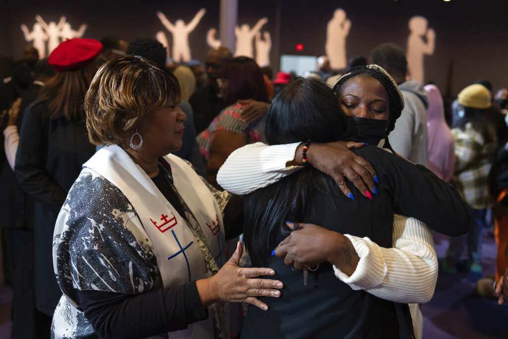 Sonya Johnson, the aunt of Tyneka Johnson, 22, of Portsmouth, Va., right in the white sweater, hugs Carmen Kingston, a loved one of Fernando "Jesus" Chavez-Barron, 16, of Chesapeake, Va., during a prayer vigil held by the Chesapeake Coalition of Black Pastors at The Mount (Mount Lebanon Baptist Church) in Chesapeake, Va.