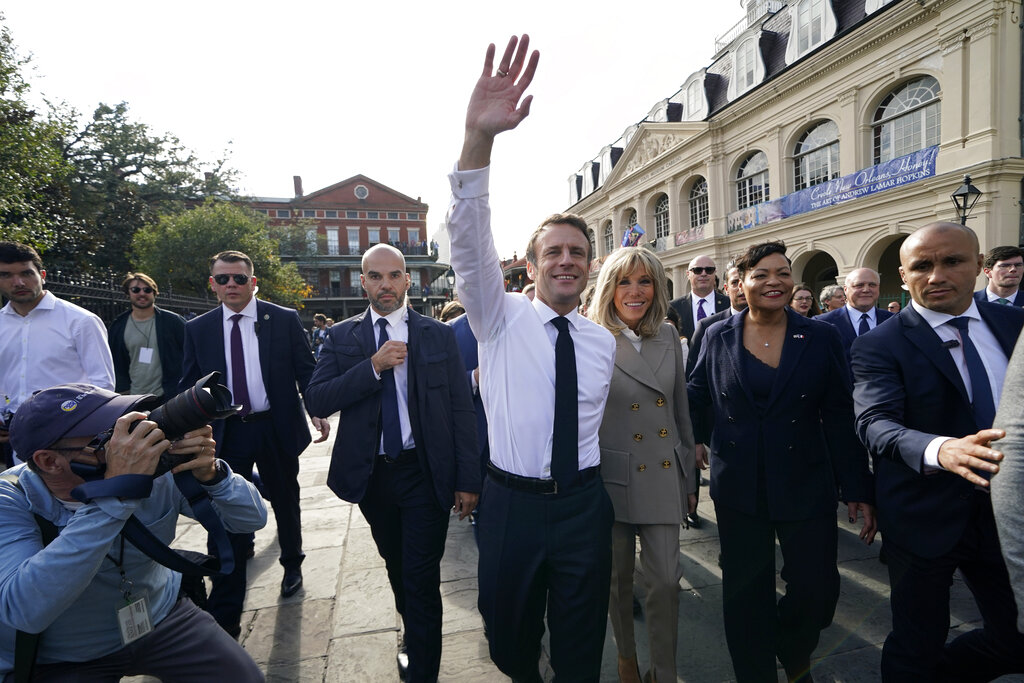 French President Emmanuel Macron waves as he walks with his wife Brigitte Macron and New Orleans Mayor Latoya Cantrell, right, as he arrives at Jackson Square in New Orleans