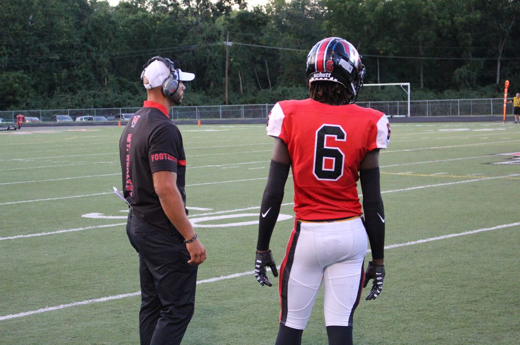 Coach Jordan Stevens and football player on the field