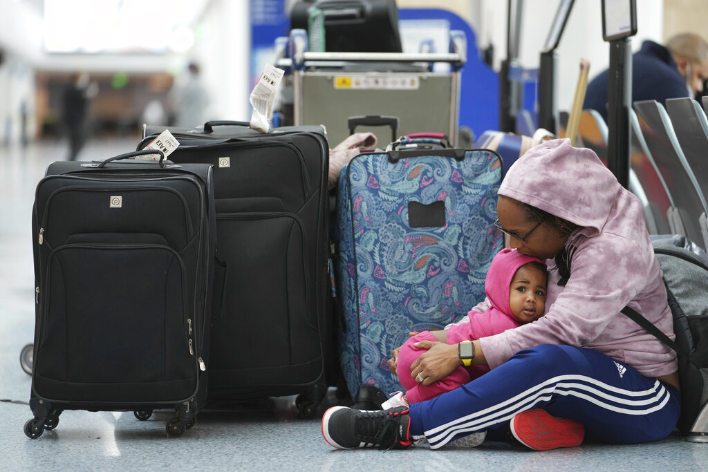 Stranded passenger, Gwendolyn Johnston, of Dallas, holds her 14-month-old daughter, Madison, as she waits with family members at the Southwest terminal at the Los Angeles International Airport