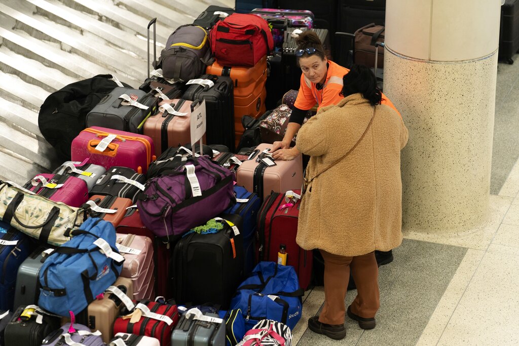 A Southwest Airlines employee helps a traveler search for bags amongst hundreds of other checked bags at baggage claim at Midway International Airport