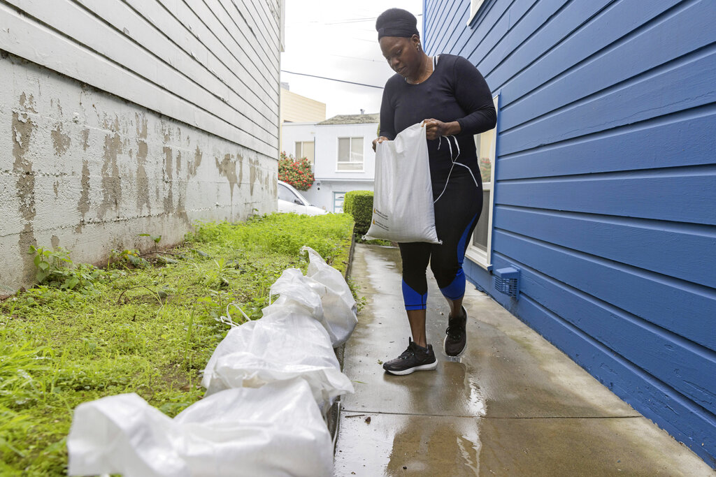 Woman puts down sandbags in an attempt to prevent flooding from storm in San Francisco