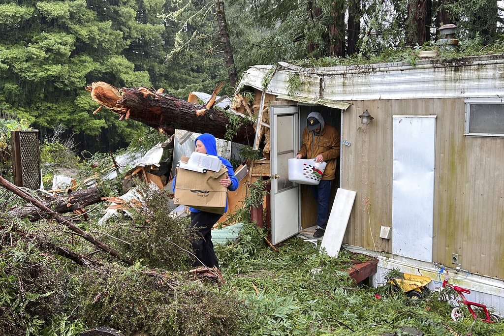 Family friends remove items from the mobile home where 2-year-old Aeon Tocchini was killed by a fallen redwood tree in Occidental, Calif.