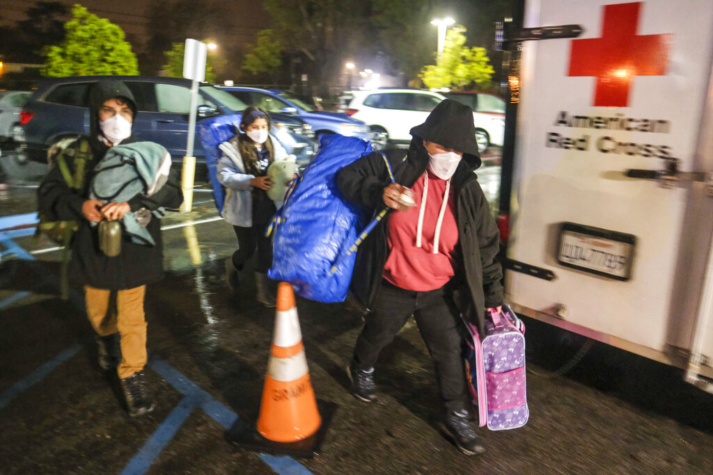 People carrying their belongings arrive at an evacuation center in Santa Barbara, Calif.