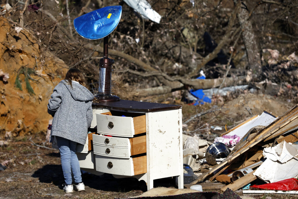 Brayleigh Johnson looks through her dresser for personal items as they recover from a tornado that ripped through Central Alabama 