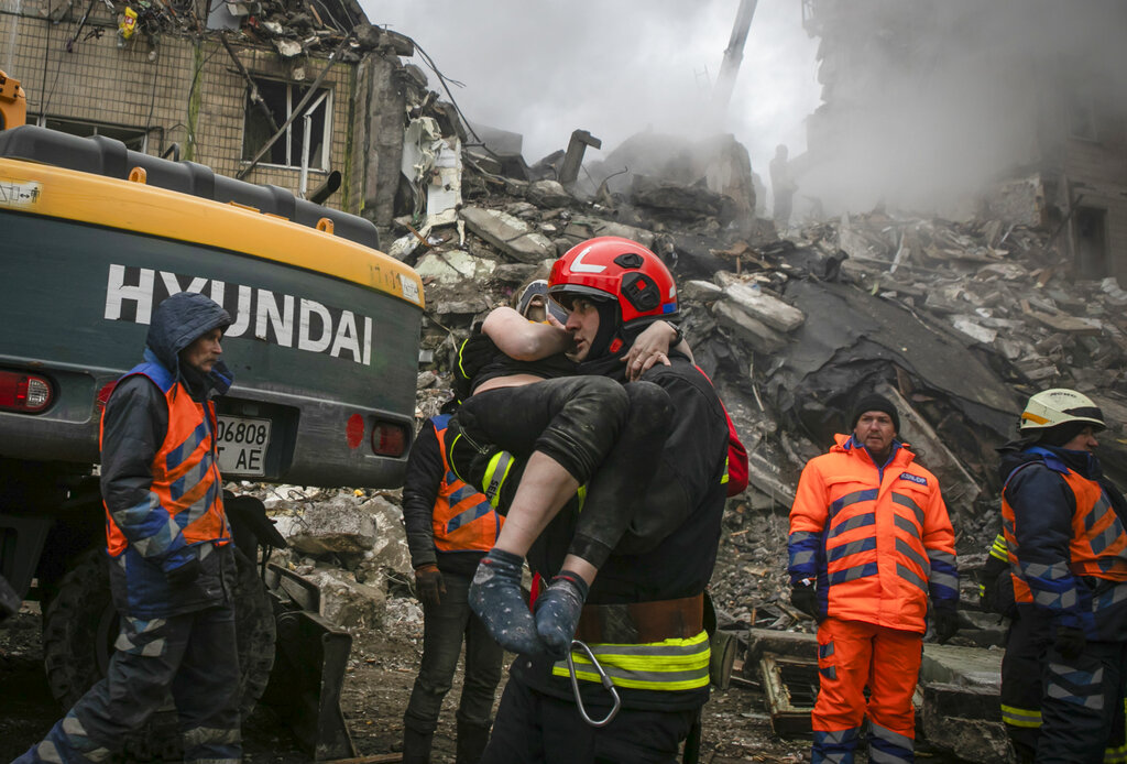 Emergency workers carry an injured woman after a Russian rocket hit a multistory building on Saturday in Dnipro, Ukraine